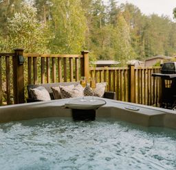A hot tub with outdoor furniture and barbecue at Spitfire Lodge in Fair Oak