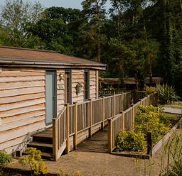 A cabin with a wooden deck and pathway at Spitfire Lodge in Fair Oak