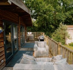 An outdoor deck with chairs and a grill at Spitfire Lodge in Fair Oak