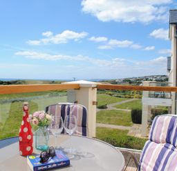 A balcony with a table and glasses at 8 Thurlestone Beach in Kingsbridge