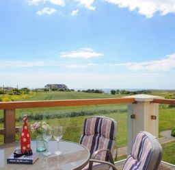 A terrace with a table and chairs overlooking a field at 8 Thurlestone Beach in Kingsbridge