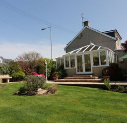 A garden with a conservatory and patio area at Llwyn Derw in Talybont