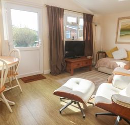 A living room with a sofa and dining area at Chalet 225 in Tregolds near St Merryn
