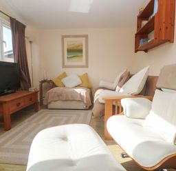 A living room with a television and sofa at Chalet 225 Tregolds near St Merryn