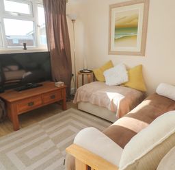 A living room with a television and sofa at Chalet 225 Tregolds near St Merryn