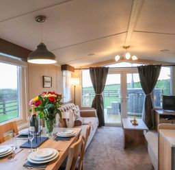 A living room with a dining area and windows at Swift Cabin Scarborough