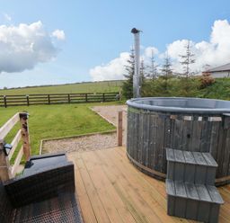 An outdoor area with a hot tub and seating at Swift Cabin in Staintondale near Scarborough