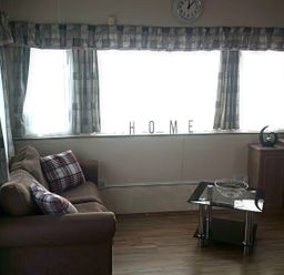 A living room with a clock and sofa at Coopers Beach Holiday Park - Holiday Accommodation 3999 Mersea Island