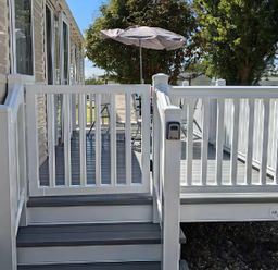A deck with railing, steps, and an umbrella at Coopers Beach Holiday Park - Holiday Accommodation 6404 Mersea Island