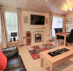 A living room with a fireplace and dining area at Kingfisher Lodge Grasmere 33 White Cross Bay near Windermere