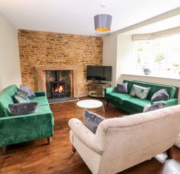 A living room with a fireplace and green sofas at The Old Bakery in Banbury