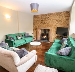 A living room with green sofas and a fireplace at The Old Bakery in Banbury