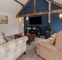 A living room with a fireplace and tv at Pillar Barn in Driffield
