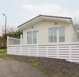 A cabin with white fencing and a gravel pathway at Beechwood Lodge in