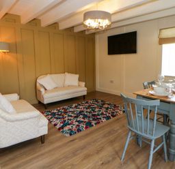 A living room with a sofa, dining table, and flat-screen TV at Shearers in Llandysul