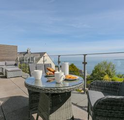 An outdoor seating area with a table and chairs at 2 Remera in St Ives