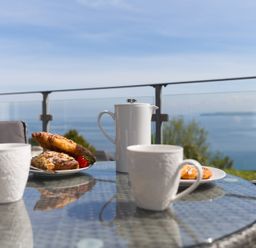 A table with cups and a teapot on a balcony at 2 Remera St Ives