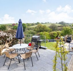 A garden with a table and chairs and a barbecue grill at Orchard View in St. Austell