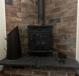 A wood stove with a flue pipe and tools on slate hearth at The Rocks in Newry