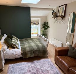 A bedroom with a bed and brown couch at Studio Apartment at High Dyke Farm, Cockermouth