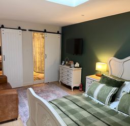 A bedroom with a bed, sofa, television, and dresser at Studio Apartment at High Dyke Farm Cockermouth