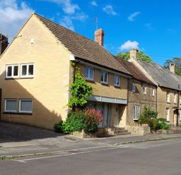 Houses along a street with a church in the background at Greenham Rise in Norton-Sub-Hamdon