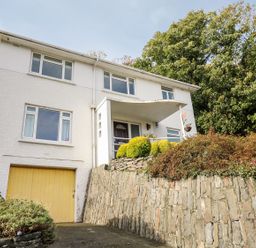 A house with a garage and stone wall at Tymelyn in Aberystwyth