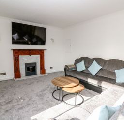 A living room with a sofa, coffee table, and fireplace at Tymelyn in Aberystwyth