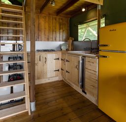 A kitchen with wooden cabinets and a yellow refrigerator at Badger - Luxury Glamping Retreat in Battle