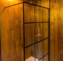 A shower enclosure with water controls and wood paneling at Badger - Luxury Glamping Retreat in Battle