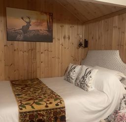 A bedroom with a bed, bedside lamps and wall art at Tylands in Camelford