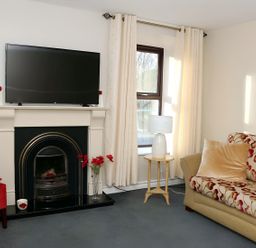 A living room with a television, fireplace, sofa, and armchair at The Farmhouse in Omagh