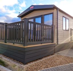 A cabin with a deck and railing at Paws By The Sea in Norwich