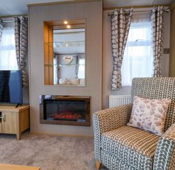 A living room with a television and armchair at Paws By The Sea in Norwich