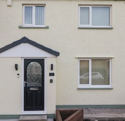 A house exterior with a black door and windows at Mables in Wigton