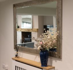 A mirror and vase with flowers on a table in a living room at 6 Front Street