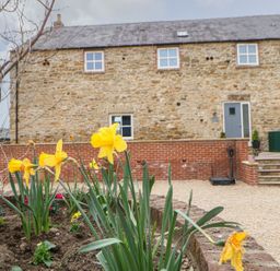 An outdoor area with flowers and a stone building at The Granary in Durham