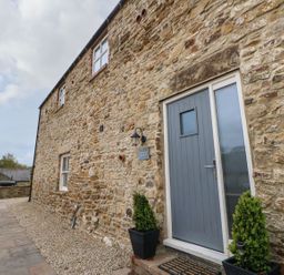 An exterior view of a stone wall with a door and planters at The Granary in Durham