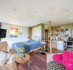 A studio with a bed, sofa, and kitchen area at The Retreat Cabin in Llanelli