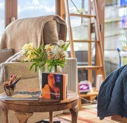 A living room with a flower vase and books on a table at The Retreat Cabin in Llanelli