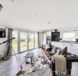 A living room with a television, sofa, and telescope at The lodge at Plumstone View in Letterston