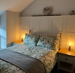 A bedroom with a bed and nightstand at Penderyn Cottage Aberdare