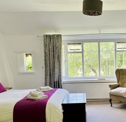 A bedroom with a bed and a chair at The Bark House in Tiverton
