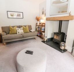 A living room with a sofa and a wood stove at East View in Cheltenham