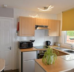 A kitchen with cupboards, stove, sink, and microwave at 228b Eighth Avenue in Bridlington