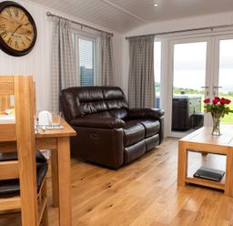 A living room with a sofa and a dining table at Nethermill Lodges in Port Glasgow