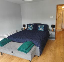 A bedroom with a bed, nightstands, towels, and a shower at 17 Castleview in Ballymena