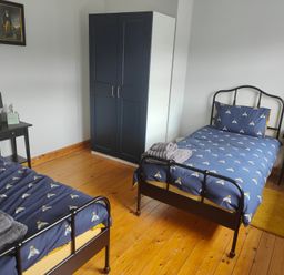A bedroom with two beds, wardrobe and nightstand at 17 Castleview in Ballymena