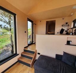 A living room with a sofa and kitchen counter at Cullinview in Isle of Skye