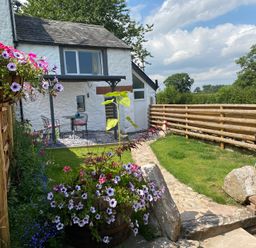 A garden with flowers, a table, and chairs at The Haven in Penrith